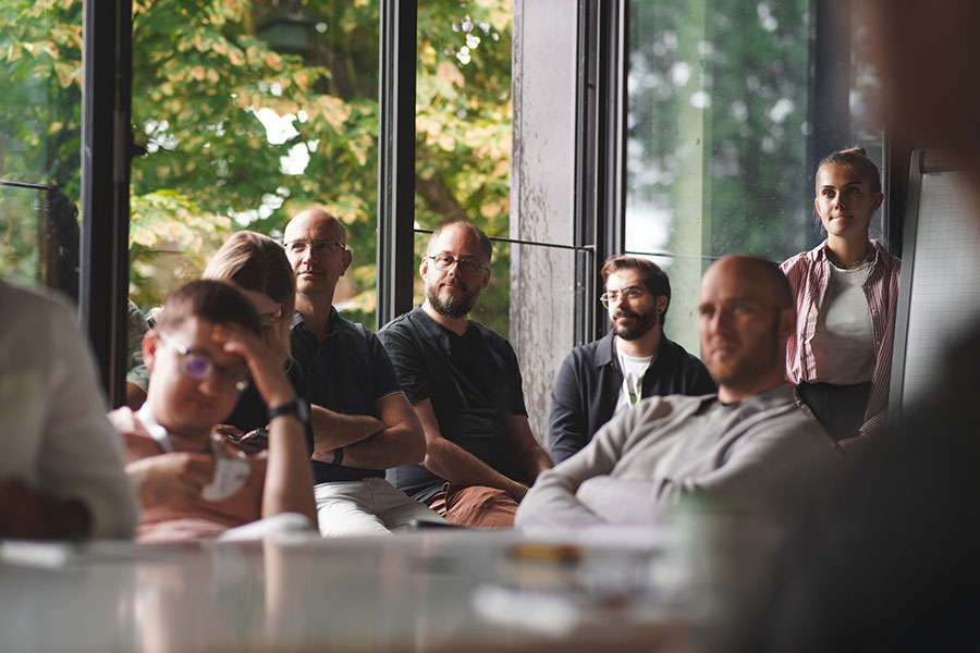 Seminar group seated in a semicircle by the windows of the oose.campus